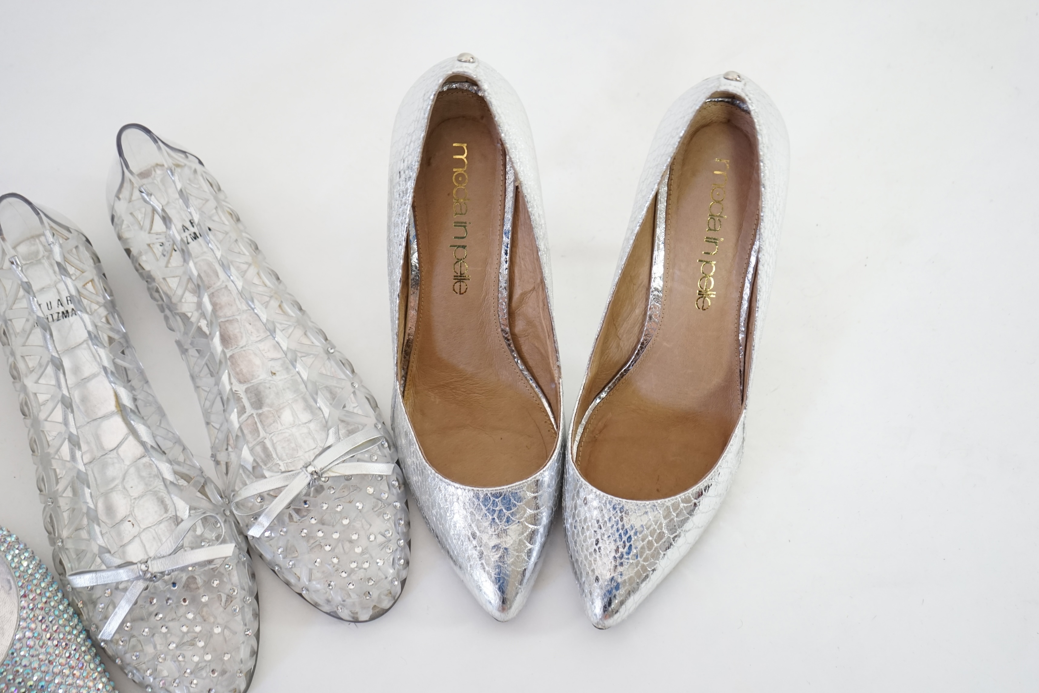 Three pairs of lady's silver shoes: Rodo silver diamonté sling back heels, Moda in Pelle silver snakeskin pattern heeled pumps and a pair of Stuart Weitzman clear jelly's with crystals. Size 38.5 (UK 4). Proceeds to Happ